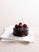 Small chocolate cake with ganache cream and cherries