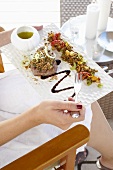 A woman holding a plate of beef fillet