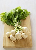 A bunch of white turnips on chopping board