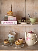 Cupcakes and tea things on wooden shelves