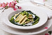 Pasta with spinach filling on spinach and peas