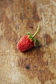 A woodland strawberry on a wooden surface