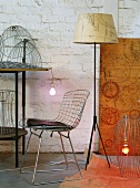 Classic wire chair and 50s-style standard lamp surrounded by lampshade frames in artistic lighting workshop