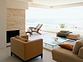 Moderne Sofagarnitur vor offener Fensterfront mit Ausblick auf Terrasse und Meer