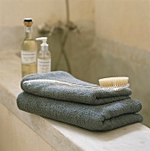 Towels, bath brush and bath essences on edge of bathtub