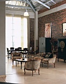 Open-plan living-dining room in loft apartment with period furniture, rough brick walls and exposed roof structure