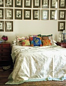 Doppelbett mit bunten Zierkissen und darüberhängender, großer Bildersammlung