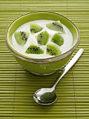 Natural yogurt with kiwis in a green bowl and spoon on the side