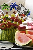 Colourful fruit kebabs stuck in a watermelon for a pirate-themed party