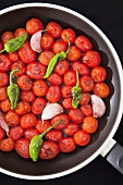 Roasted cherry tomatoes with chilli peppers and garlic in a pan