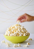 Hand nimmt Popcorn aus einer Schale