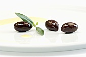 Kalamata olives with leaves and olive oil on a plate
