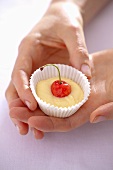 Hands holding an unbaked cherry muffin