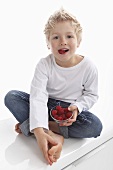 A little boy eating raspberries