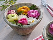 Ranunculus flowers, narcissus and floating candle in bowl