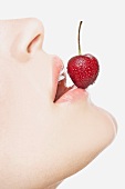 Woman balancing a cherry on her lip