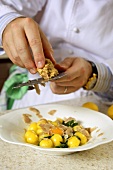 A chef shaving truffles over an egg and potato dish