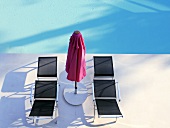 Loungers and sunshade by swimming pool