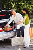 Couple packing picnic things into car boot