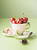 Cherry jam on spoon, fresh cherries in cup and saucer