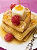 Heart-shaped pancakes with maple syrup, raspberries and butter