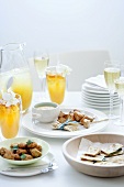 Party snacks, cocktails and sparkling wine on laid table