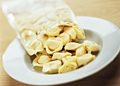 Tipping uncooked tortellini out of packaging onto plate