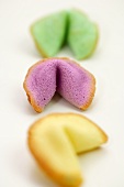 Three different-coloured fortune cookies, in a row