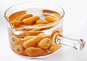 Baby carrots in water in glass pan