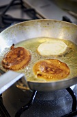 Small ricotta pancakes being fried in oil