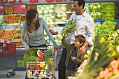 Family at supermarket vegetable counter