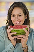 Young woman holding a slice of watermelon in her hand