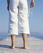 Young woman standing on a jetty with a bottle of water