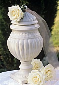 Roses ('Maroussia') beside antique-effect vase