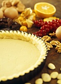 Pastry in a tart tin surrounded by baking ingredients