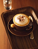 Cappuccino in brown cup and saucer with amarettini