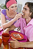Woman feeding man ham and radishes