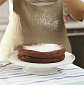 Dusting chocolate cake with icing sugar
