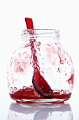 A jar with remains of raspberry jelly and spoon