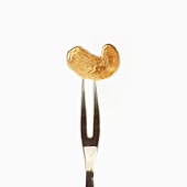 A shelled cashew nut on a meat fork