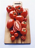Various types of tomatoes on a wooden board