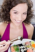 Woman eating sushi with chopsticks