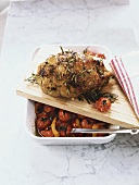 Leg of lamb studded with rosemary, baked tomatoes