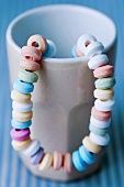 A candy necklace hanging on a cup
