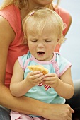 Kleines Mädchen isst pikant gefülltes Brötchen