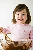 Small girl stirring cake mixture in bowl