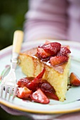 A piece of orange cake with fresh strawberries