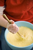 Child stirring cake mixture in a bowl