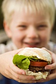 Small boy holding a burger