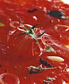 Tomatoes and spices floating in a sauce